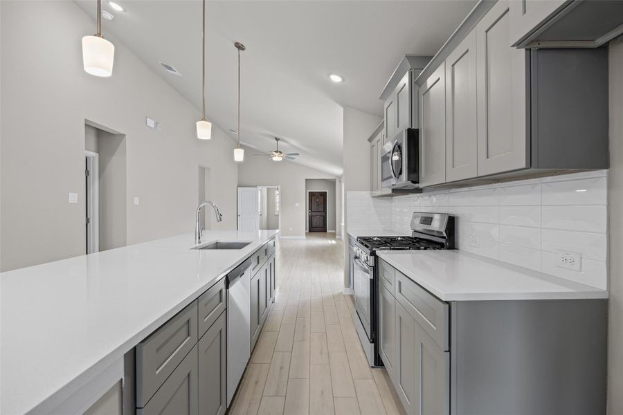 Vaulted ceilings rise above sleek stone countertops and modern cabinetry in this open culinary space. Vaulted ceilings rise above sleek stone countertops and modern cabinetry in this open culinary space.