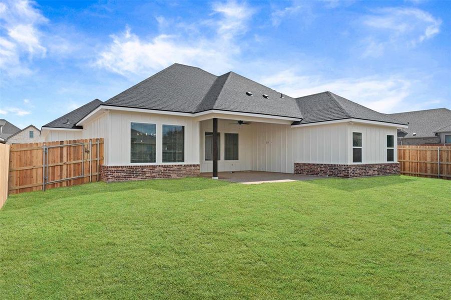 Back of house featuring a ceiling fan, brick siding, roof with shingles, and a patio area