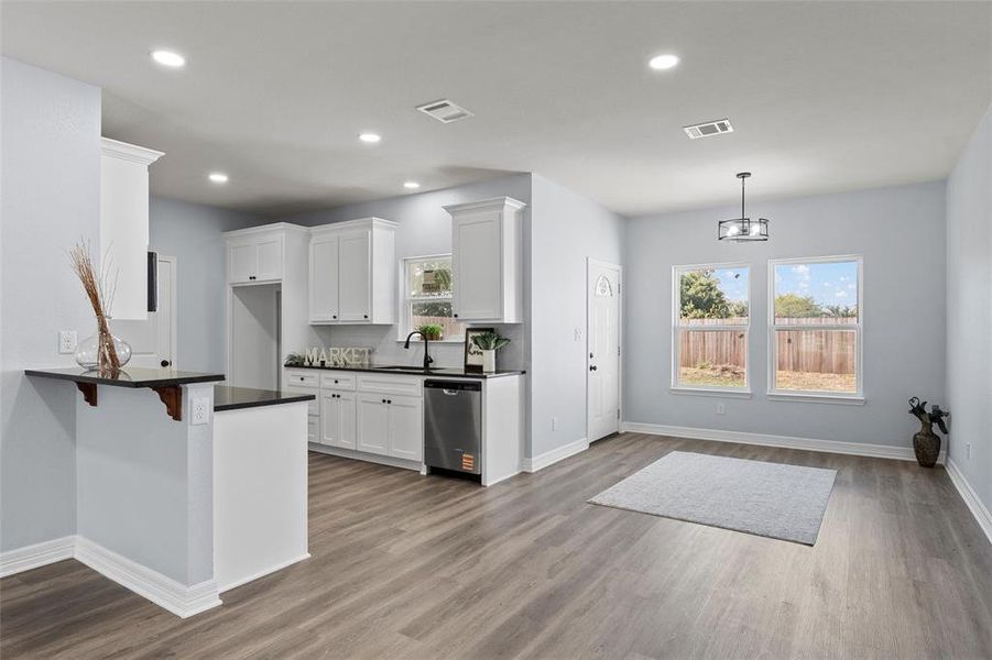 Kitchen with recessed lighting, a kitchen bar, white cabinetry, dark wood finished floors, and dishwasher