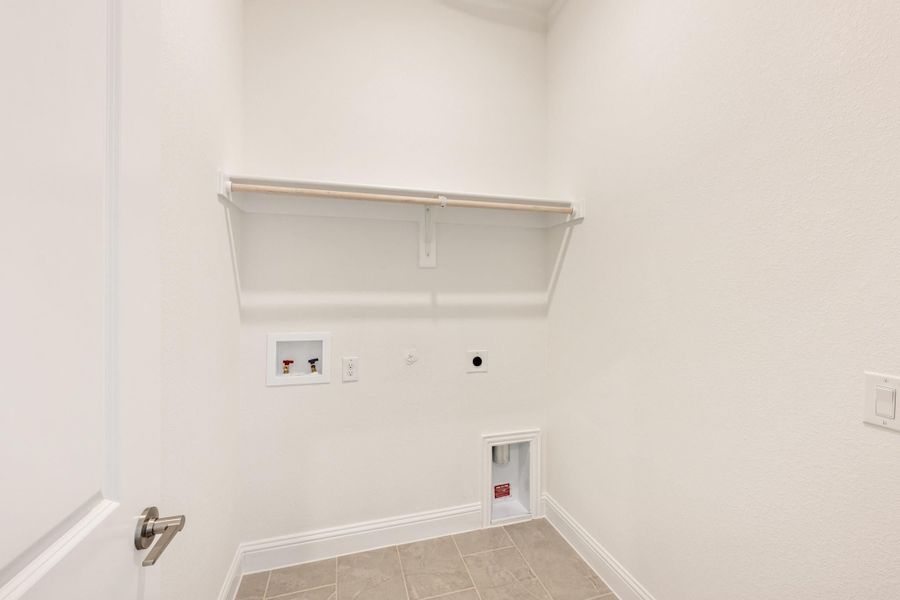 Empty laundry room with wall shelf, washer hookups, dryer vent, and tile floor Empty laundry room with wall shelf, washer hookups, dryer vent, and tile floor