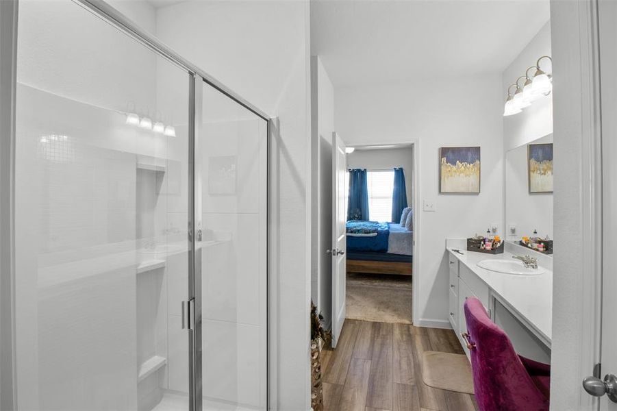Primary Bathroom with wood finished floors, vanity, ensuite bathroom, and a shower stall