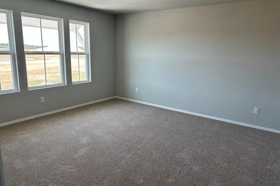 Image of home primary bedroom with light carpet, white walls, and windows Image of home primary bedroom with light carpet, white walls, and windows