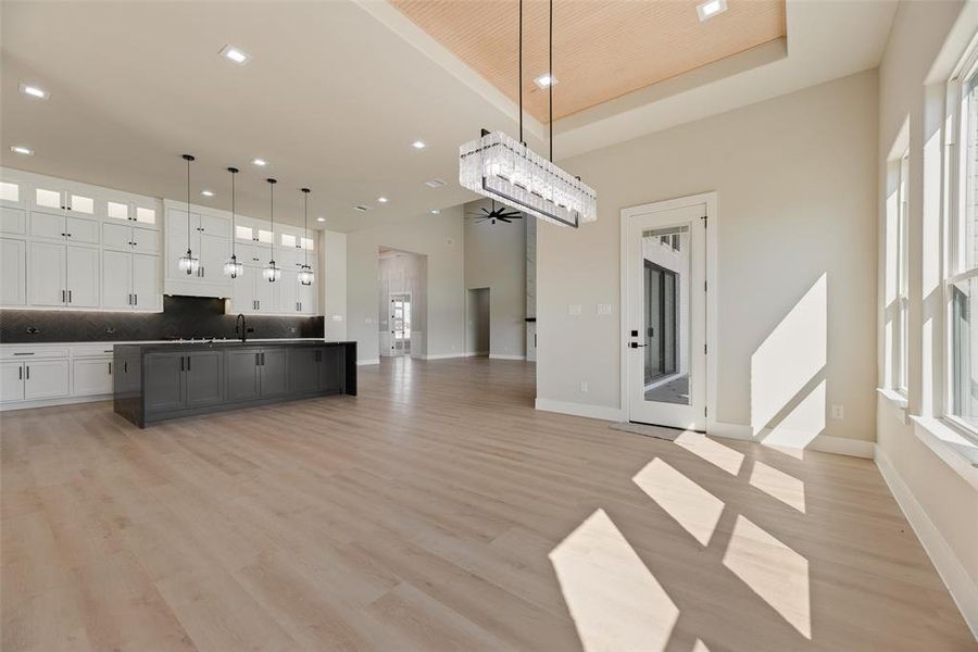 Unfurnished dining area with light wood-type flooring, recessed lighting, and a high tray ceiling