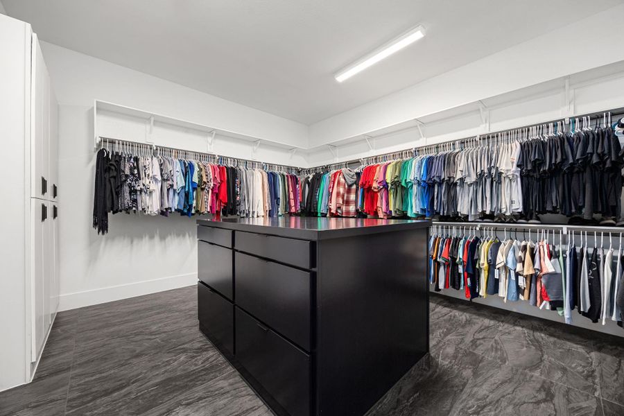 Spacious walk-in closet featuring ample hanging space, a large central island with drawers, and sleek modern design. Perfect for organization and storage. Spacious walk-in closet featuring ample hanging space, a large central island with drawers, and sleek modern design. Perfect for organization and storage.