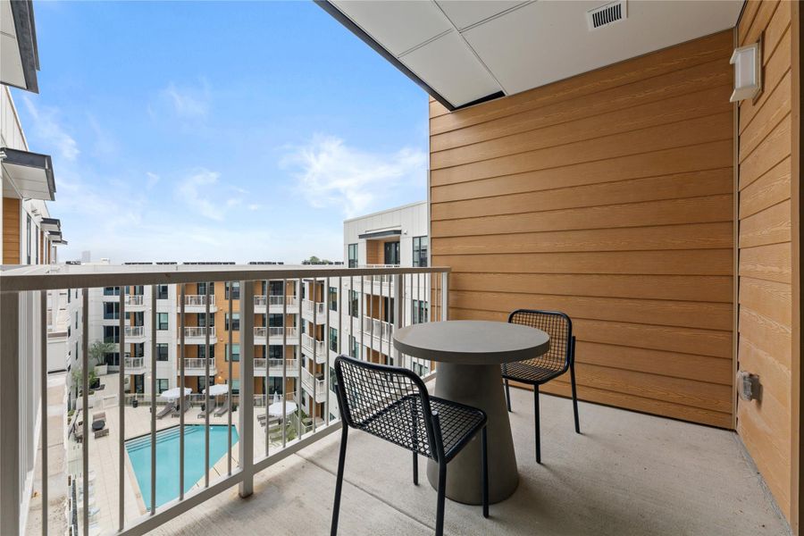 An elevated private balcony overlooks a shared courtyard swimming pool. An elevated private balcony overlooks a shared courtyard swimming pool.