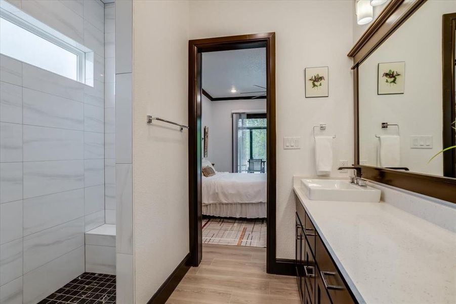 Ensuite bathroom with vanity, a walk in shower, light tile-style floors, and ornamental molding