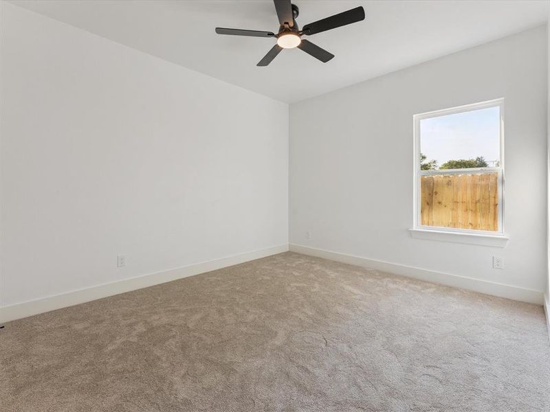 Carpeted spare room with baseboards and a ceiling fan