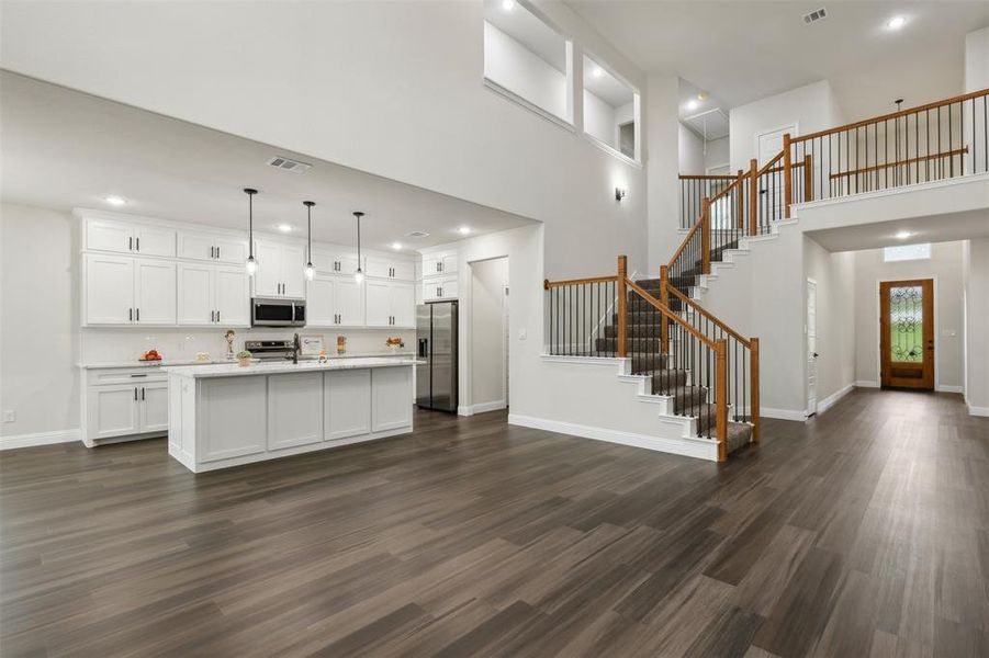 Kitchen featuring dark hardwood / wood-style flooring, stainless steel appliances, an island with sink, and white cabinetry