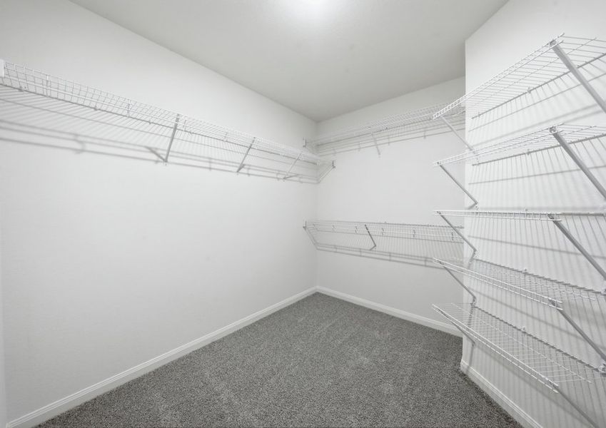 Primary walk-in closet featuring built-in wire shelving. Primary walk-in closet featuring built-in wire shelving.