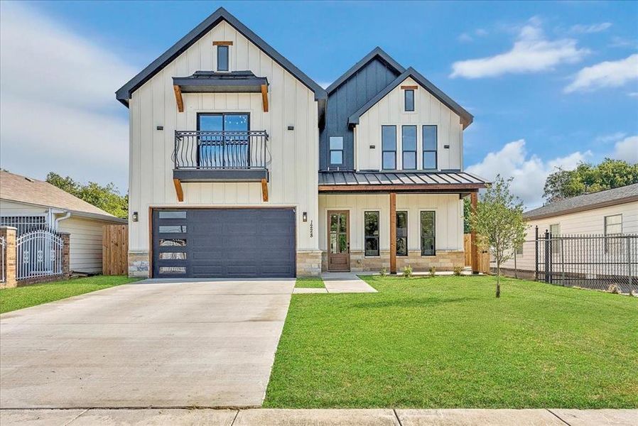 Modern farmhouse featuring board and batten siding, a standing seam roof, an attached garage, driveway, and a metal roof