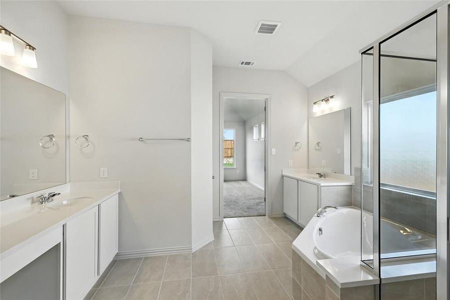 Full bathroom featuring two vanities, a bath, light tile patterned floors, a shower stall, and lofted ceiling