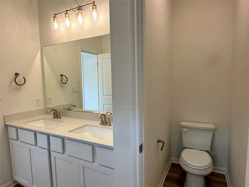 Bathroom with double vanity and dark wood-style floors
