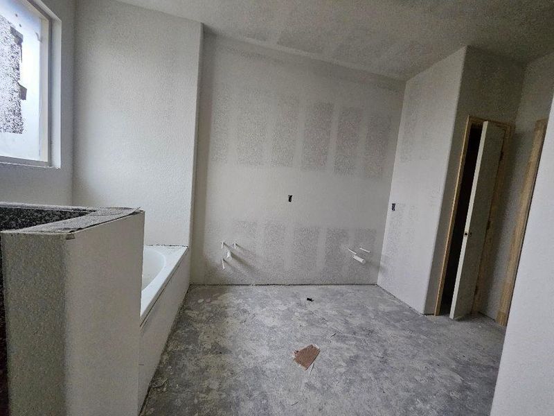 Bathroom under construction featuring a built-in bathtub, a window, and exposed drywall Bathroom under construction featuring a built-in bathtub, a window, and exposed drywall