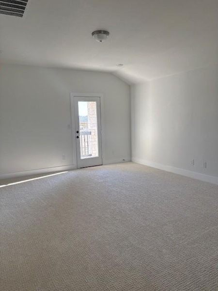 Carpeted spare room featuring lofted ceiling, baseboards, and visible vents