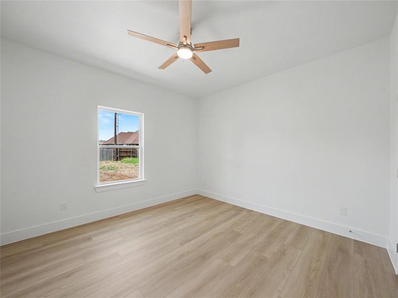 Neutral white walls featuring a single window and light wood-finish flooring Neutral white walls featuring a single window and light wood-finish flooring