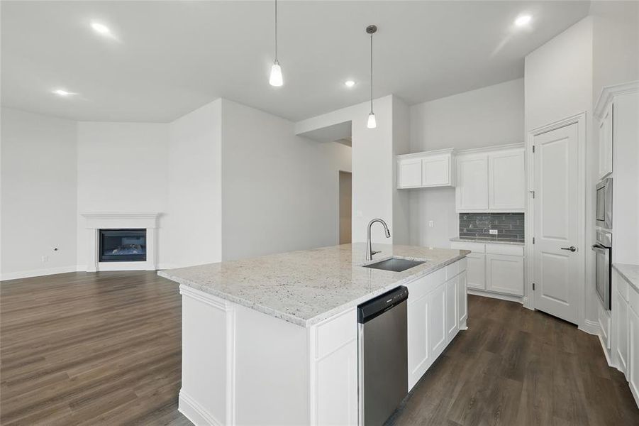 Kitchen with decorative backsplash, appliances with stainless steel finishes, dark wood finished floors, a sink, and light stone counters