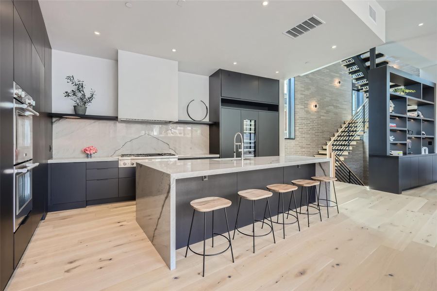 A sleek, contemporary kitchen with pristine stone counters and built-in appliances, flowing into an open-concept living space. A sleek, contemporary kitchen with pristine stone counters and built-in appliances, flowing into an open-concept living space.