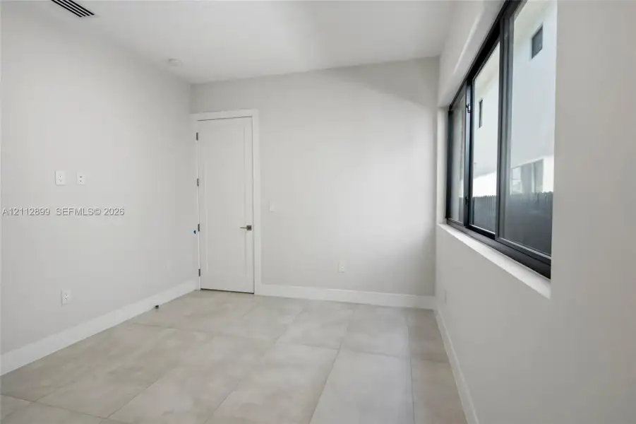 Room featuring large-format ceramic tile flooring, neutral wall paint, and a multi-pane window with dark frames