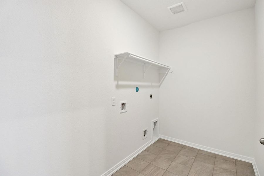 Beyond the kitchen is the laundry room which features a streamlined shelf to keep all your essentials neatly within reach.