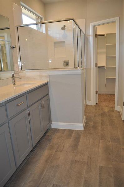 Bathroom with hardwood / wood-style flooring, vanity, and a shower with door