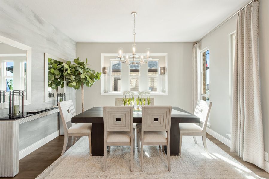 Formal dining room with dark wood table, white chairs, chandelier, and large windows