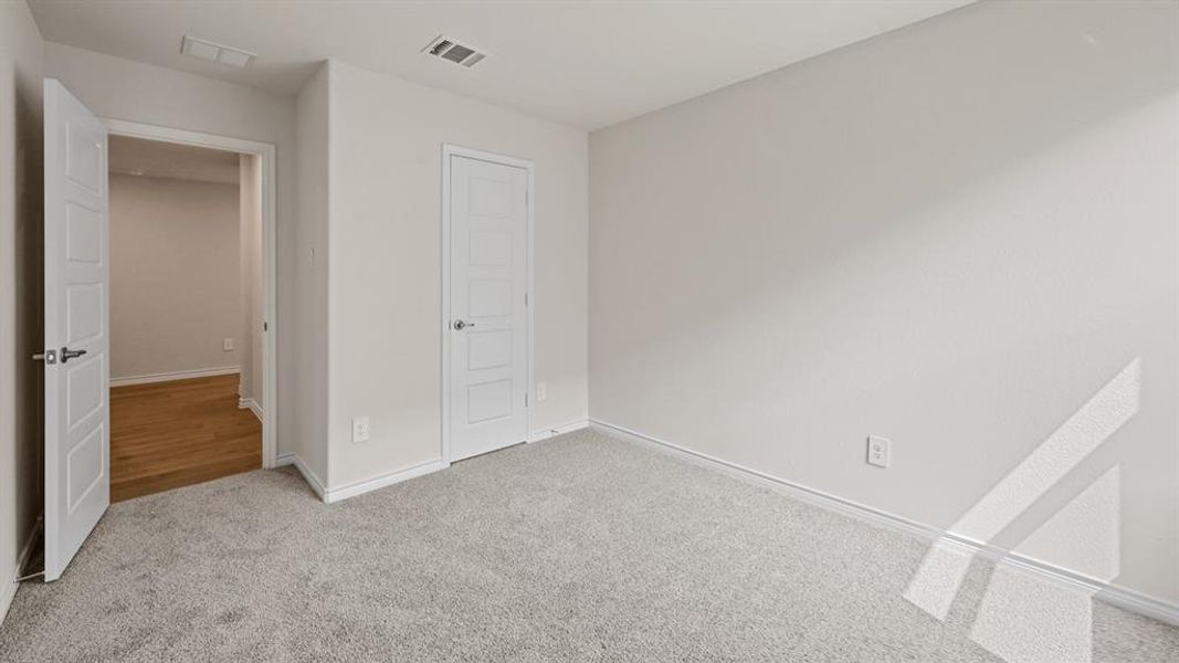 Carpeted room featuring light gray walls, white trim, and two modern five-panel doors with brushed nickel hardware Carpeted room featuring light gray walls, white trim, and two modern five-panel doors with brushed nickel hardware