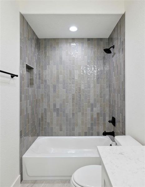 Bathroom featuring tiled shower / bath combo and toilet