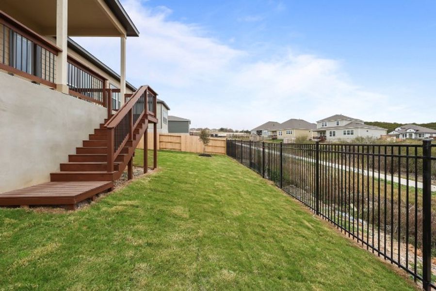 A fenced in yard with a house in the background. A fenced in yard with a house in the background.