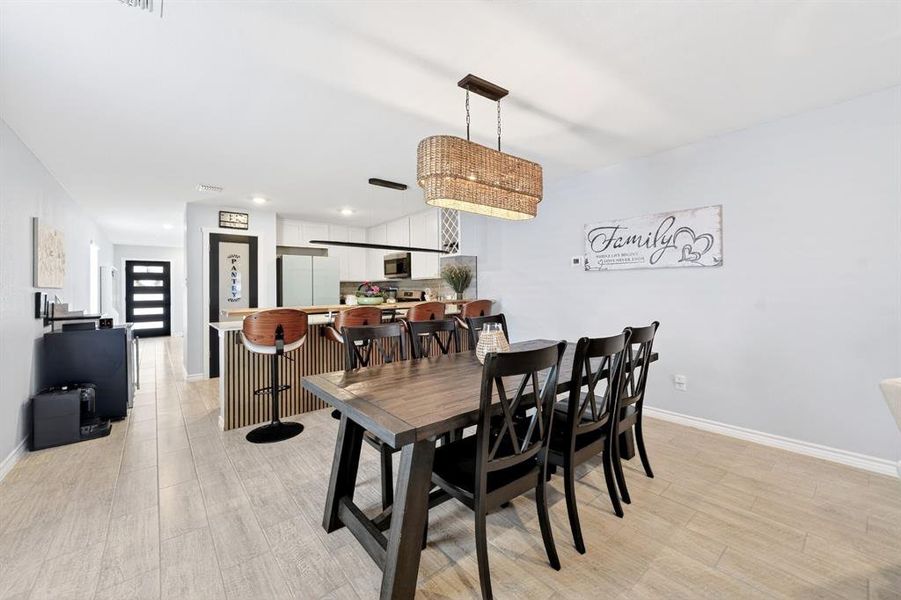 Dining area featuring plank-style flooring, a woven pendant light fixture, and a dark wood-finish dining table