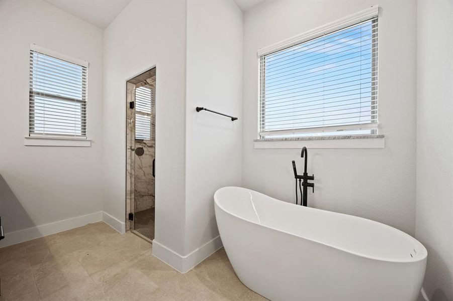 Bathroom with a freestanding bath, a shower stall, and baseboards