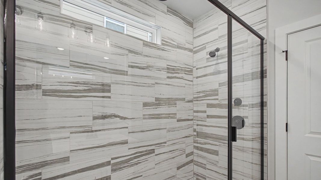 Luxury tiled walk-in shower with glass doors and mutiple shower heads