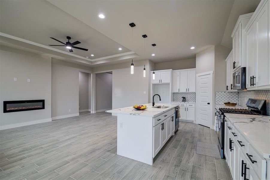 Kitchen featuring stainless steel appliances, white cabinetry, and a kitchen island with sink