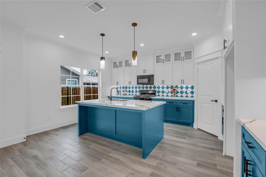 This kitchen combines vibrant blue cabinetry with a chic island and eye-catching tile backsplash, creating a bright and inviting space perfect for breakfast gatherings.