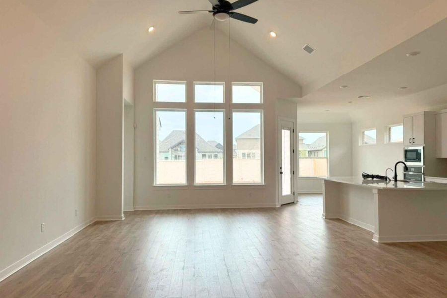 Unfurnished living room featuring light wood finished floors, a high ceiling, ceiling fan, and recessed lighting