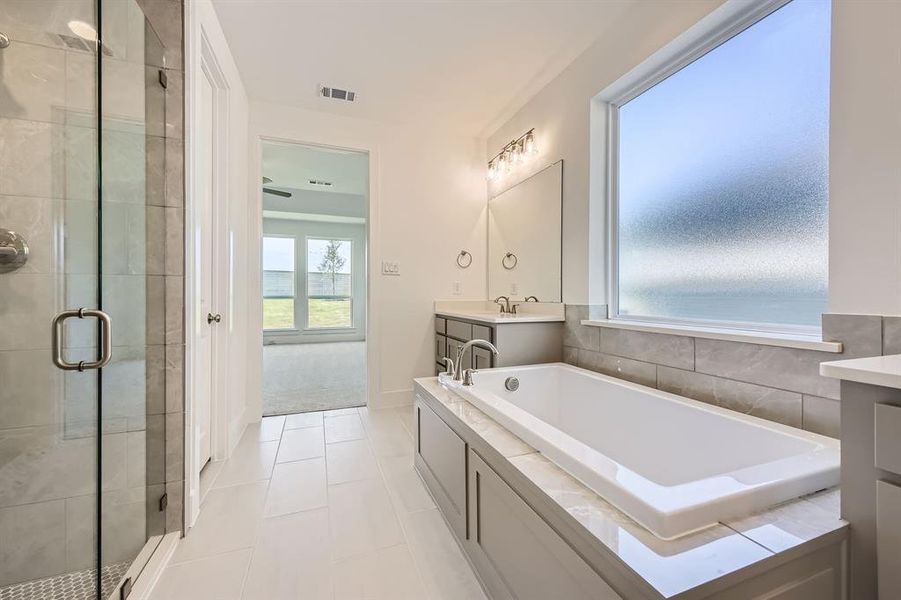 Full bath featuring a stall shower, a garden tub, vanity, and tile patterned floors Full bath featuring a stall shower, a garden tub, vanity, and tile patterned floors