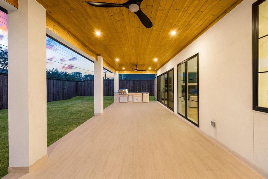 Fenced backyard featuring exterior kitchen, a ceiling fan, and a patio area Fenced backyard featuring exterior kitchen, a ceiling fan, and a patio area