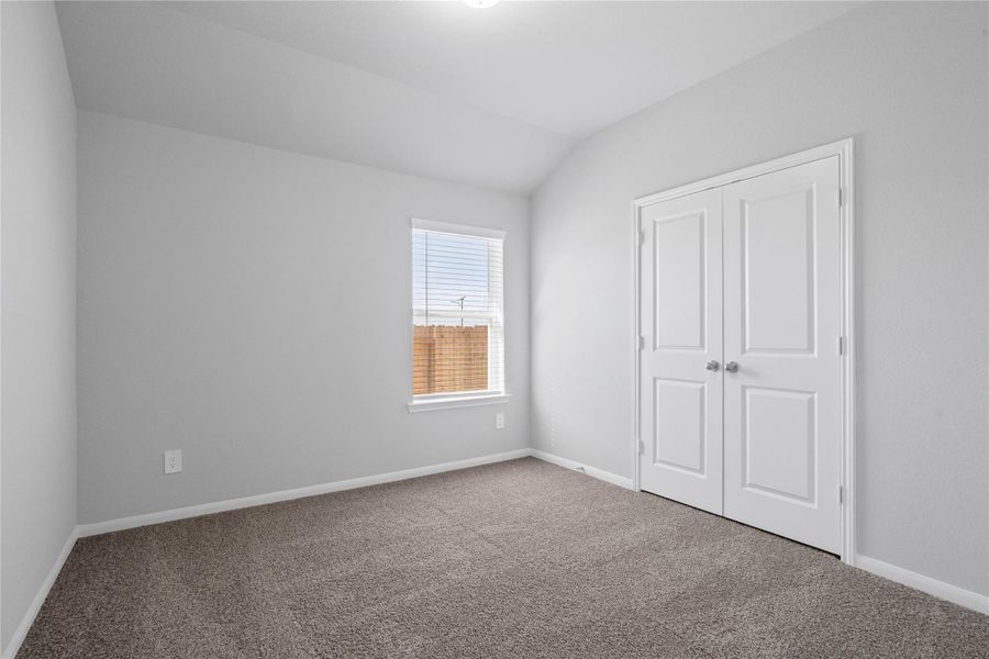 This cozy secondary bedroom offers plush soft carpeting, neutral walls ready for personalization, a sun-filled window with fitted blinds, sloped ceilings, and a spacious closet for all your storage needs.