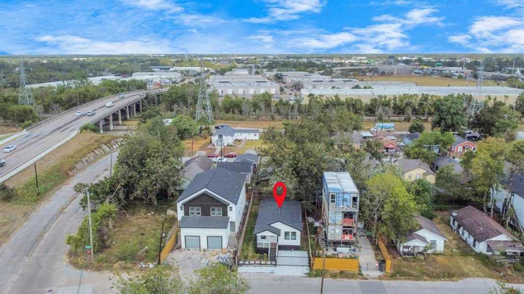 This aerial photo shows a vacant residential lot delineated by a red boundary, situated between two houses, with mature trees and greenery, providing a potential site for building a new home in an established neighborhood.