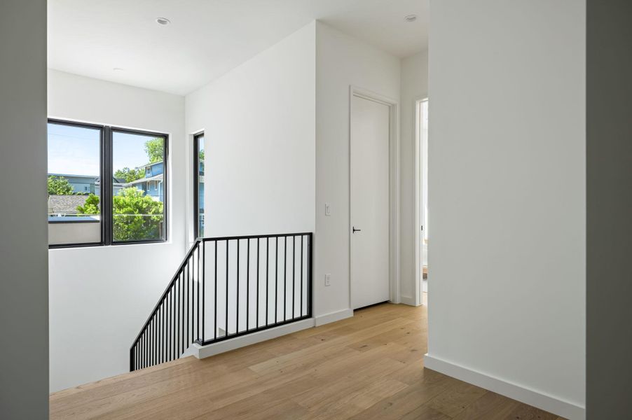 Minimalist design and warm hardwood flooring define this welcoming upper-level landing.