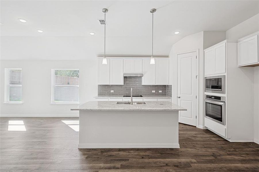 Kitchen featuring white cabinets, dark hardwood / wood-style floors, light stone counters, and appliances with stainless steel finishes