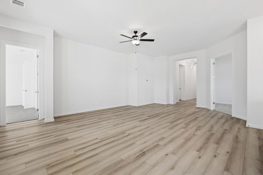 Unfurnished living room with light wood-type flooring, a ceiling fan, and a chandelier Unfurnished living room with light wood-type flooring, a ceiling fan, and a chandelier