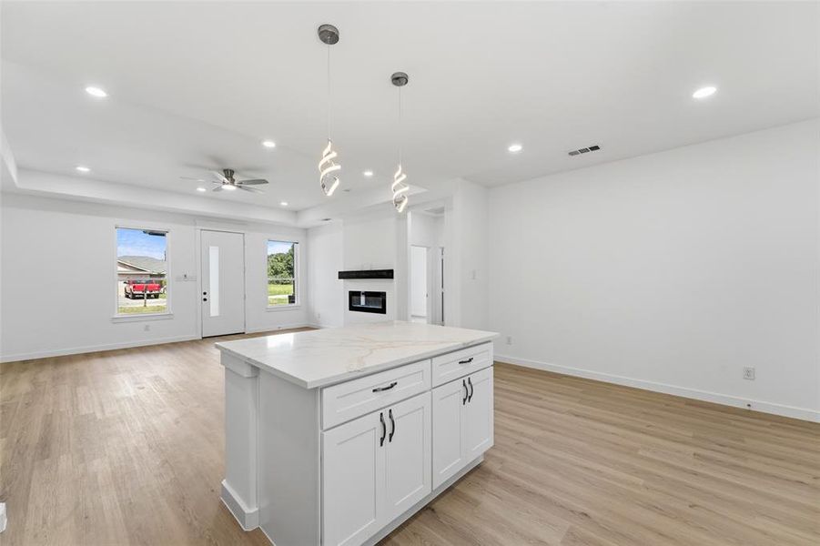 Central kitchen island featuring a light-toned countertop and white cabinetry with dark hardware