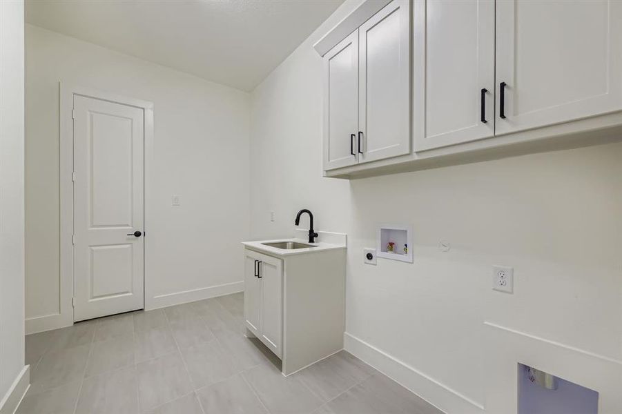 Washroom featuring washer hookup, light tile patterned flooring, cabinet space, gas dryer hookup, and electric dryer hookup Washroom featuring washer hookup, light tile patterned flooring, cabinet space, gas dryer hookup, and electric dryer hookup