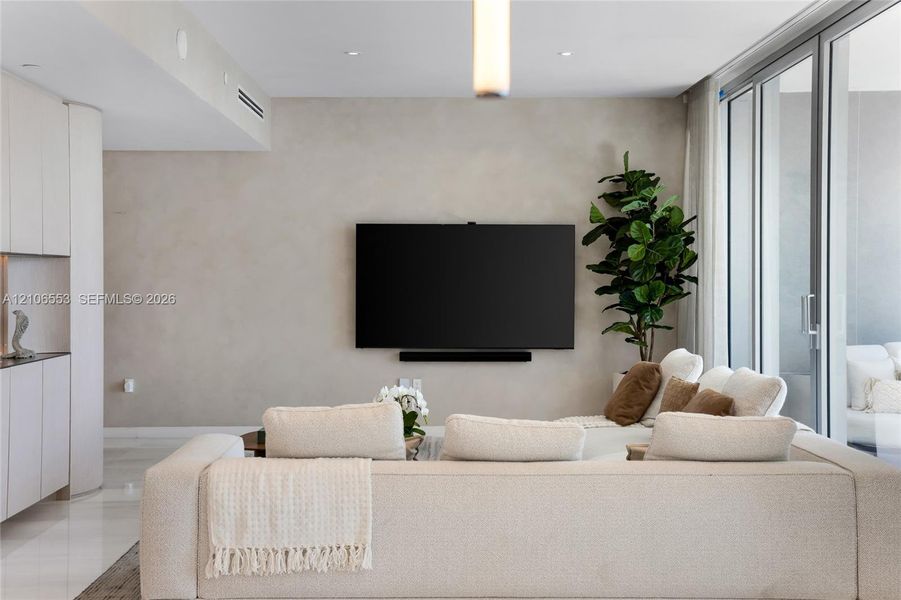 Living area featuring smooth-finish walls, floor-to-ceiling sliding glass doors, polished stone flooring, and recessed ceiling lighting