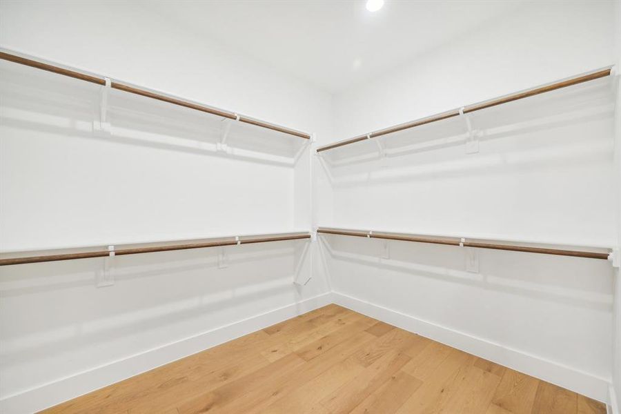 Walk in closet with hardwood / wood-style flooring