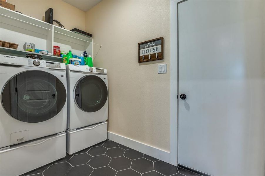 Laundry area with dark tile patterned floors, and new washer and dryer Laundry area with dark tile patterned floors, and new washer and dryer