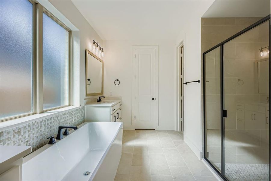 Bathroom with a soaking tub, vanity, a stall shower, light tile patterned floors, and backsplash Bathroom with a soaking tub, vanity, a stall shower, light tile patterned floors, and backsplash