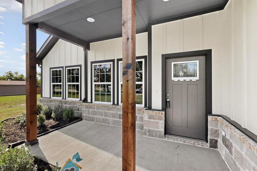 Doorway to property with covered porch, board and batten siding, and stone siding Doorway to property with covered porch, board and batten siding, and stone siding
