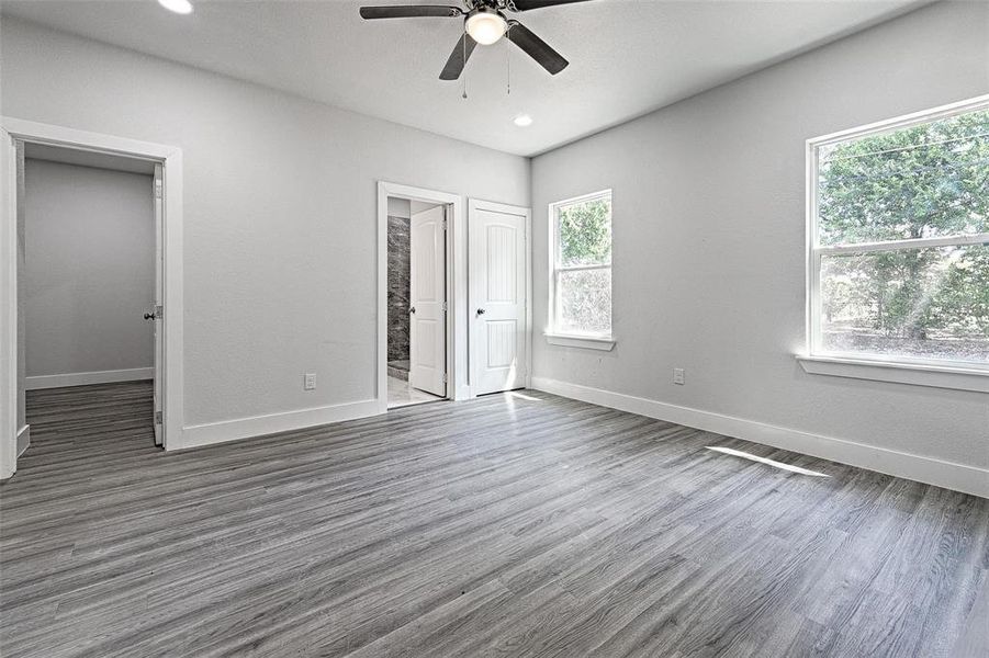 Unfurnished bedroom with ensuite bathroom, ceiling fan, dark hardwood / wood-style flooring, and a closet