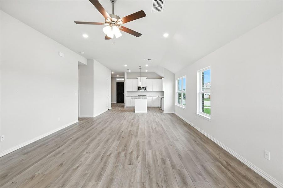 Unfurnished living room featuring vaulted ceiling, light wood-type flooring, ceiling fan, and recessed lighting